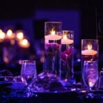 Elegant candlelit table setting with floating candles and glassware—ideal ambiance for corporate events in Dallas, TX.