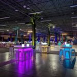 Spacious indoor venue with neon-lit high-top tables and modern décor—customizable for corporate events in Dallas, TX.