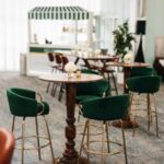 Chic indoor lounge setup with green velvet bar chairs and wood tables—stylish setting for corporate events in Dallas, TX.