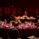Formal round table event setup with red linens and floral centerpieces—expertly arranged by a top DFW DMC for corporate galas or banquets.