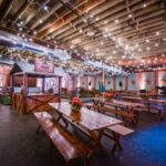 Rustic indoor event venue with picnic tables, string lights, and themed décor—perfect for casual events organized by a DFW DMC.