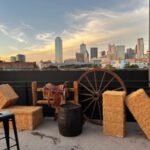 Western-themed rooftop setup with hay bales and wagon wheel overlooking the Dallas skyline—iconic event concept by a DFW DMC.