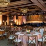 Spacious ballroom set with round tables, elegant draping, and chandeliers—expertly planned by a North Texas DMC for a formal gala.