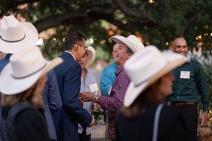 Attendees in cowboy hats enjoying a conversation at an outdoor gathering—casual networking experience designed by Texas corporate event planners.